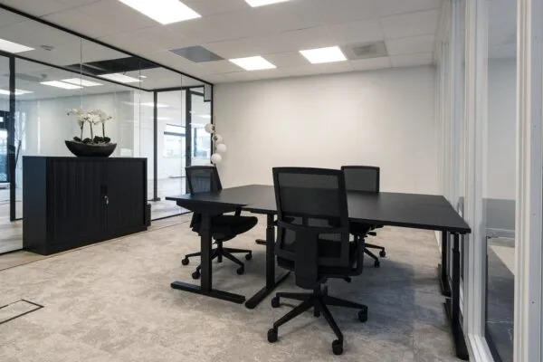 Moderne, lichte kantoorruimte in Hoofddorp met zwarte bureaus, bureaustoelen en glazen wanden.