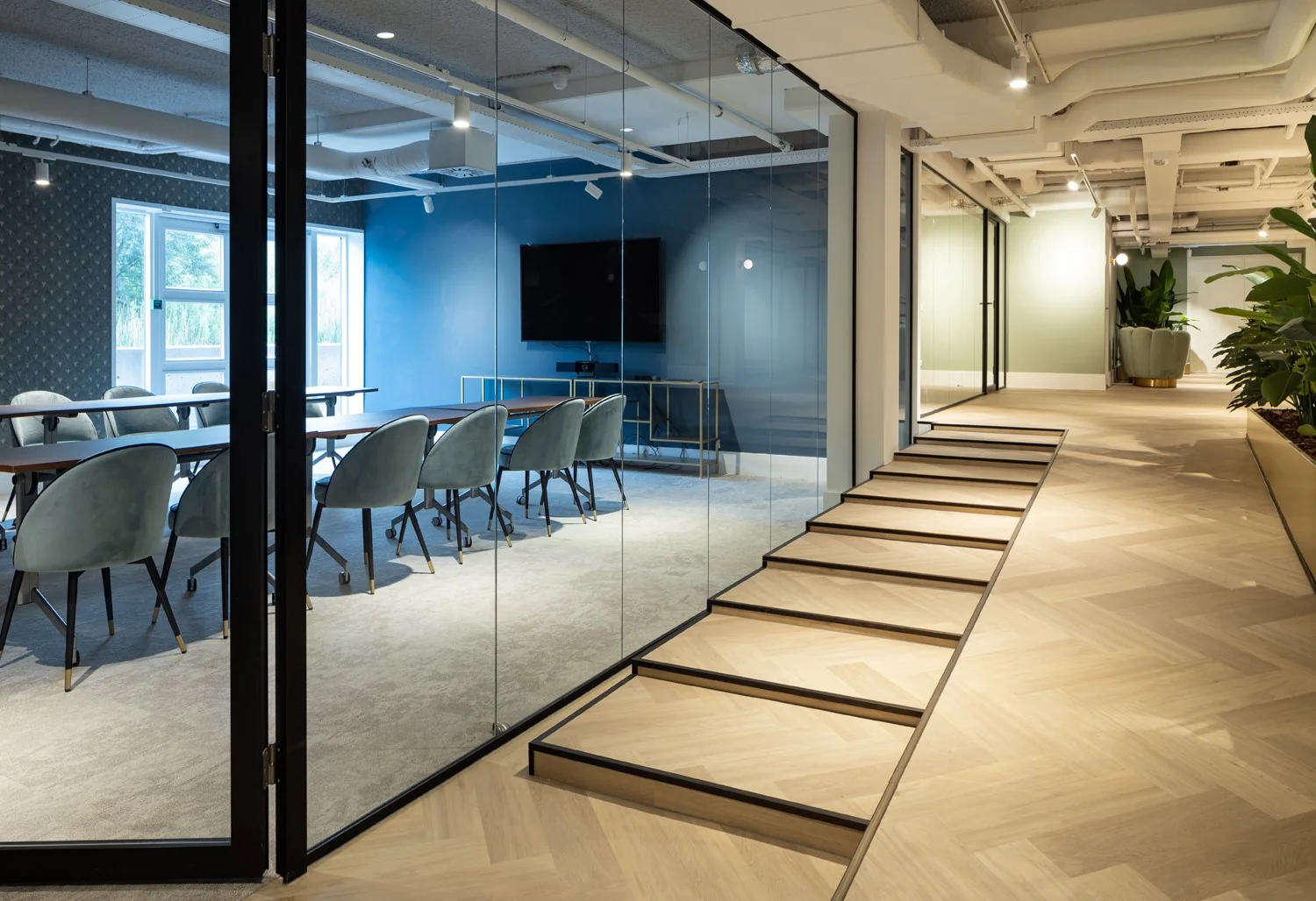 Moderne kantoorruimte in Hoofddorp met glazen vergaderruimte, houten vloer en veel natuurlijk licht.