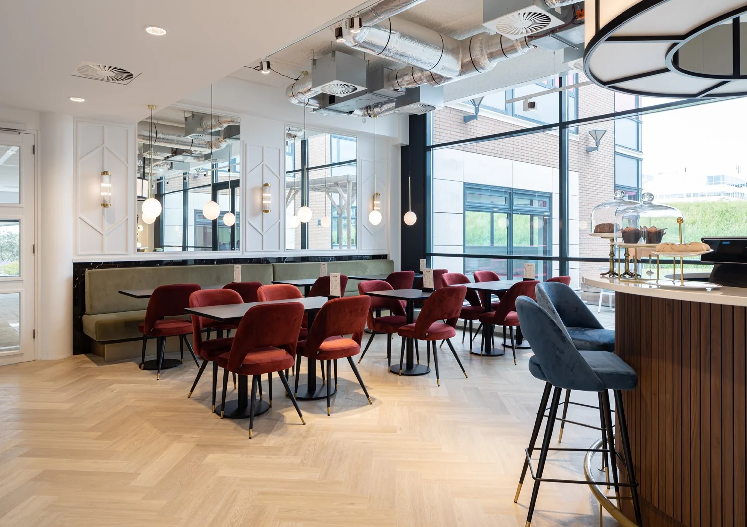 Moderne kantoorruimte in Hoofddorp met stijlvolle zithoeken, houten vloer en een koffiebar met gebak.