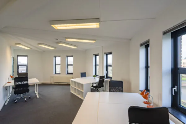 Moderne en lichte kantoorruimte met meerdere bureaus en grote ramen in Hoofdveste 2 in Houten.
