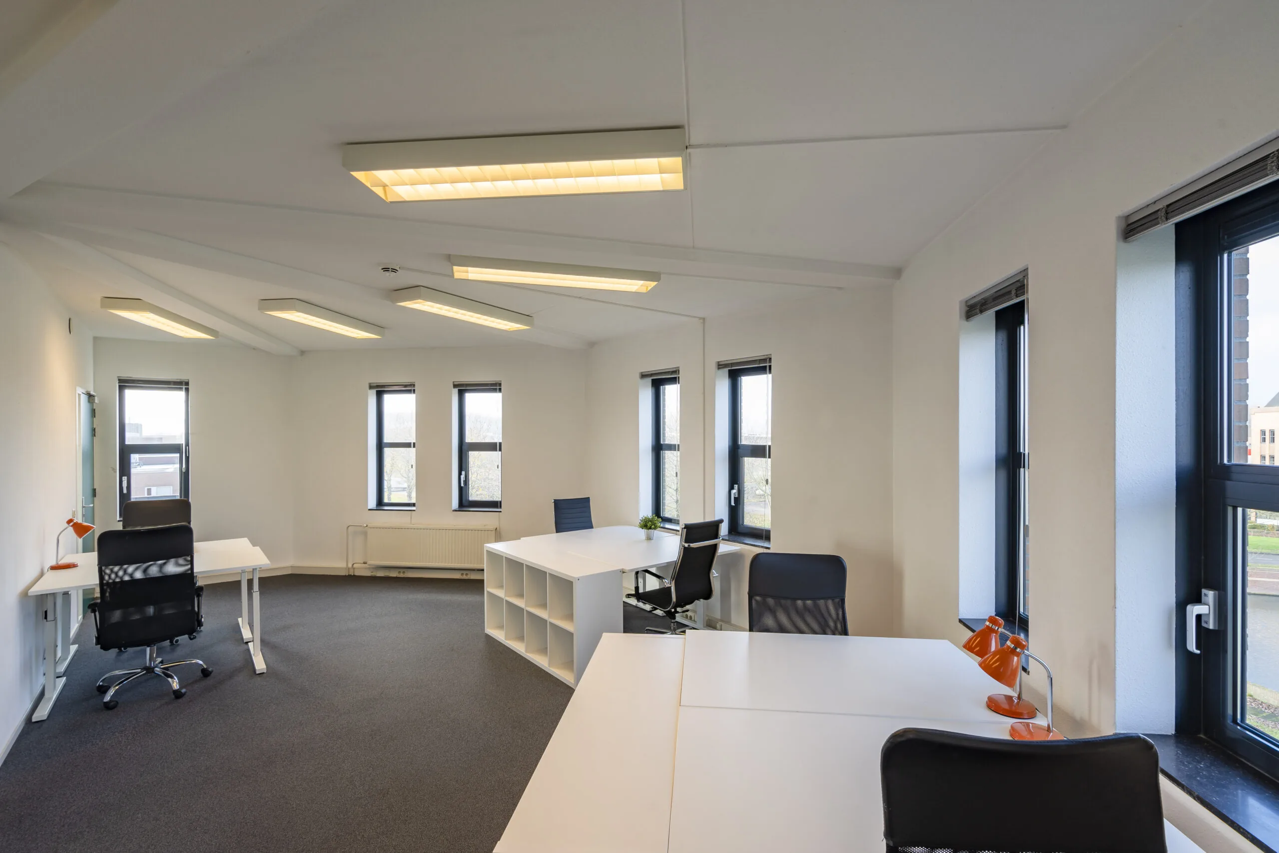 Moderne en lichte kantoorruimte met meerdere bureaus en grote ramen in Hoofdveste 2 in Houten.