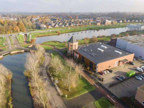 Luchtfoto van het kantoorgebouw aan Hoofdveste 2 in Houten, gelegen aan het water met parkeerplaatsen en omliggende infrastructuur.