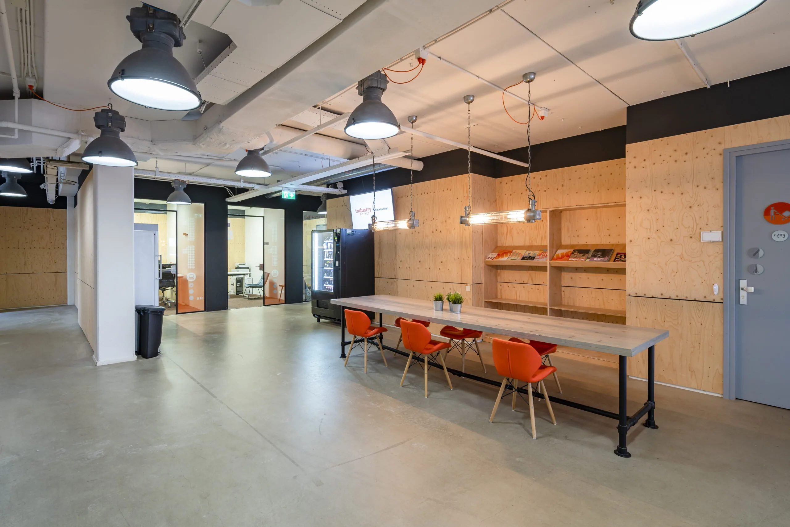Moderne kantoorruimte aan de Innsbruckweg 103 in Rotterdam met houten wanden, lange werktafel en oranje stoelen.