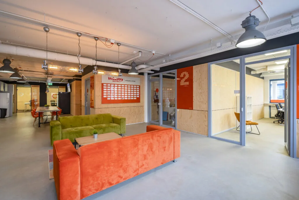 Moderne, kleurrijke kantoorruimte aan de Innsbruckweg 103 in Rotterdam met open zithoek en glazen vergaderruimtes.