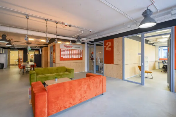 Moderne, kleurrijke kantoorruimte aan de Innsbruckweg 103 in Rotterdam met open zithoek en glazen vergaderruimtes.