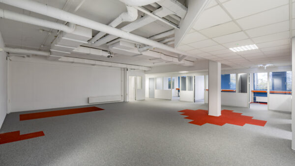 Moderne kantoorruimte aan de Innsbruckweg 103 in Rotterdam met grijs tapijt, rode accenten en zicht op aparte kantoorunits.