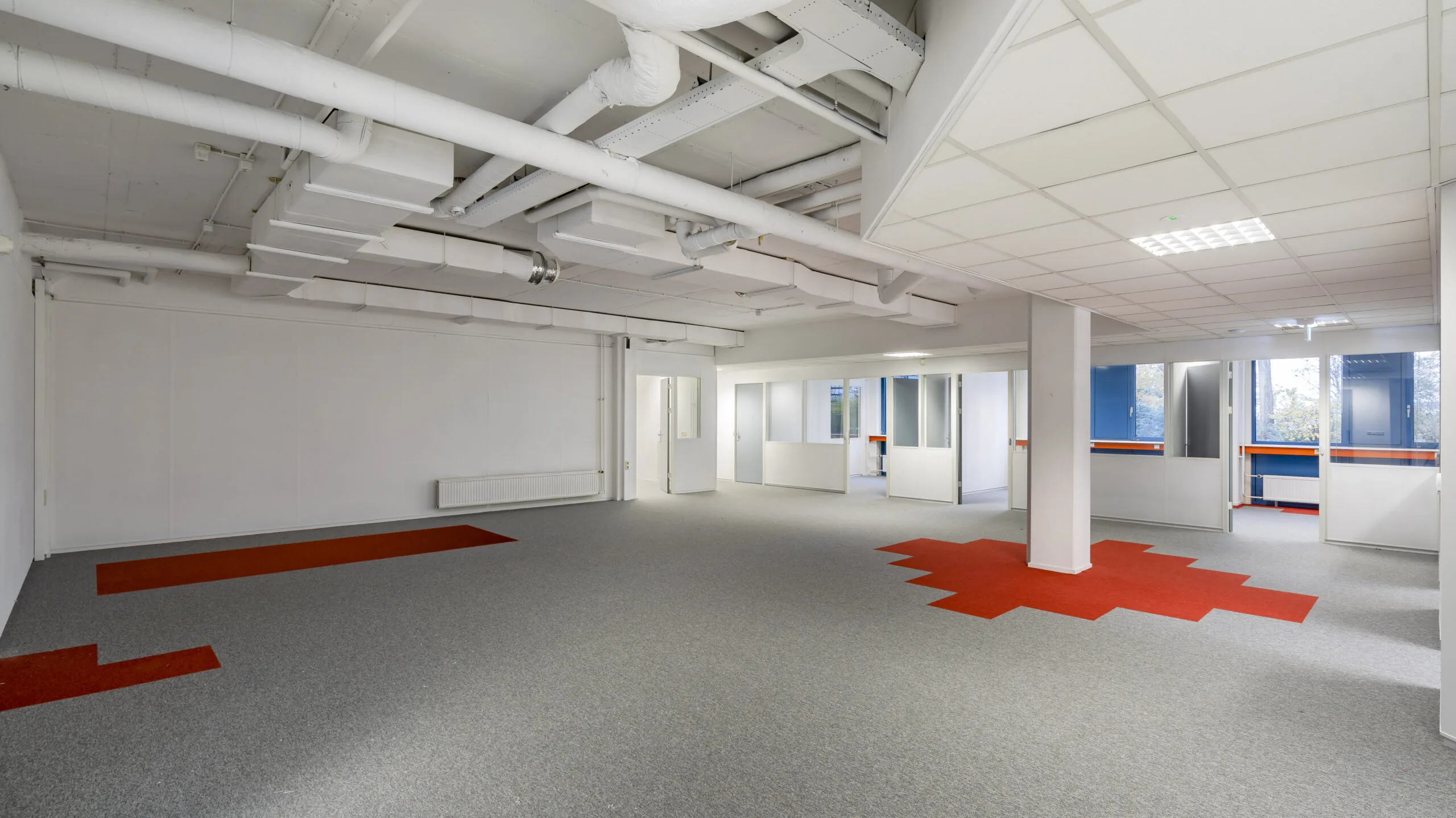 Moderne kantoorruimte aan de Innsbruckweg 103 in Rotterdam met grijs tapijt, rode accenten en zicht op aparte kantoorunits.