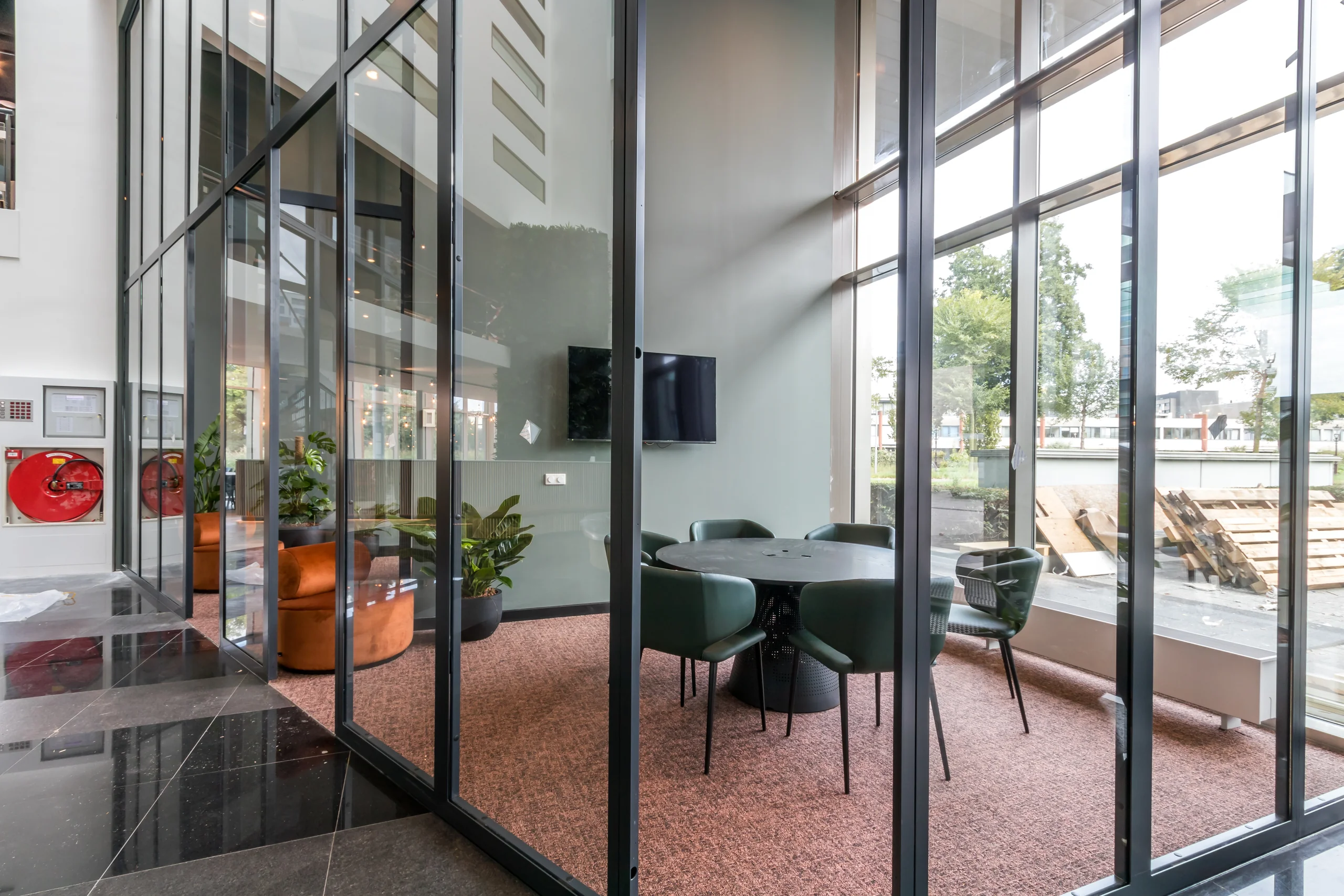 Moderne vergaderruimte met glazen wanden, ronde tafel en vijf stoelen in een kantoorpand aan het John M. Keynesplein 10 in Amsterdam.