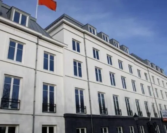 Wit kantoorpand met meerdere verdiepingen aan de Koninginnegracht 19 in Den Haag, met een rode vlag op het dak.