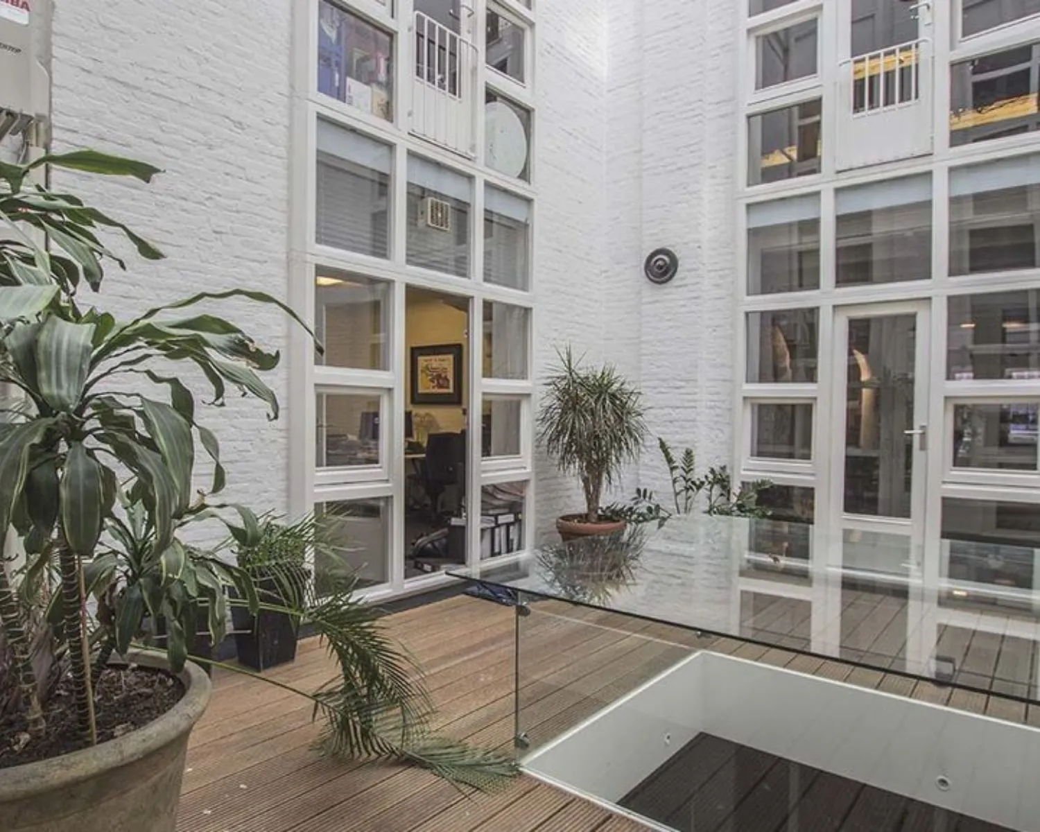 Moderne kantoorruimte met glazen vloer en planten in een lichte binnentuin aan de Korte Leidsedwarsstraat 12 in Amsterdam.