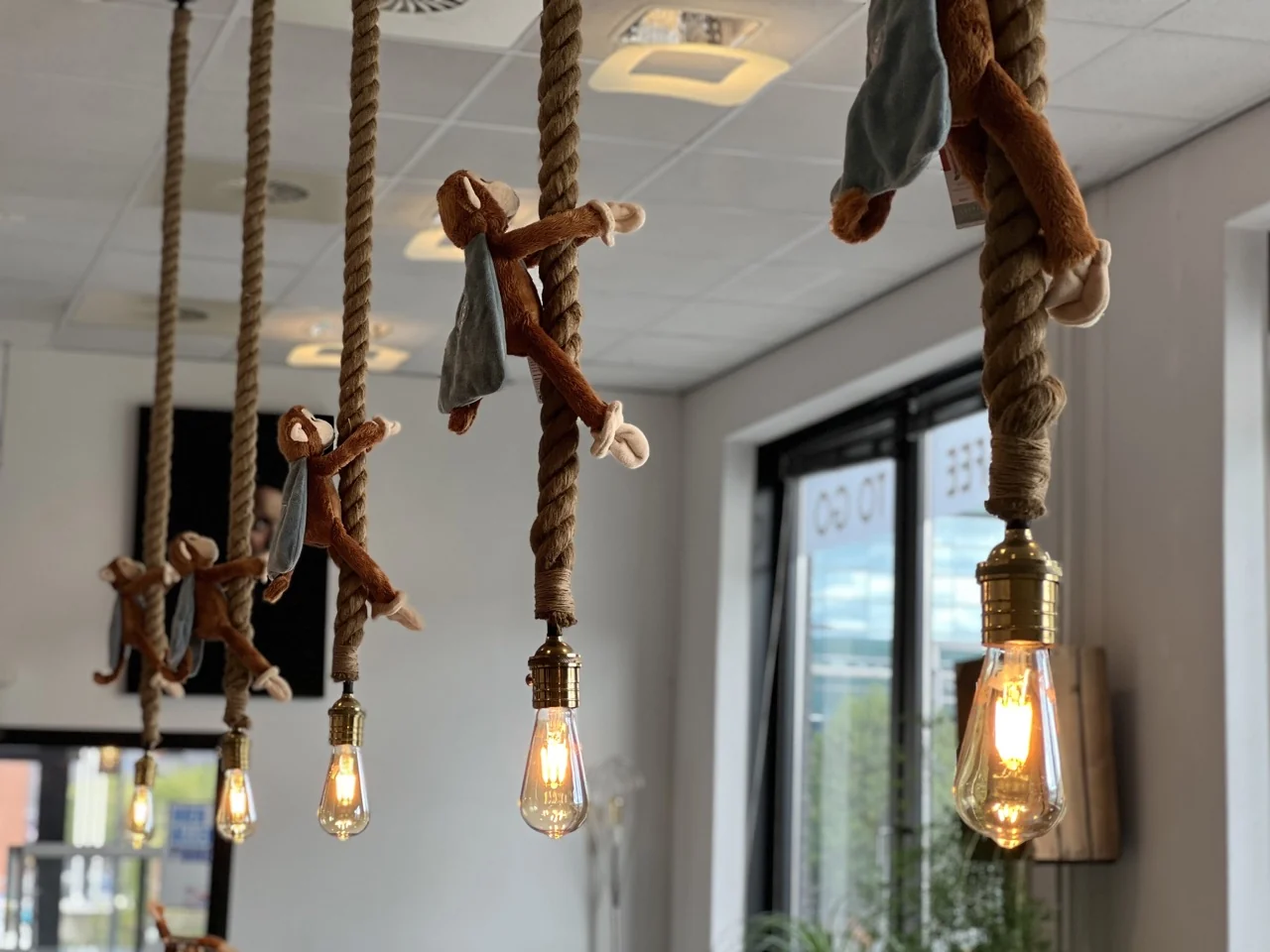 Pluche aapjes hangen aan touwlampen in een creatieve kantoorruimte aan de Lange Kleiweg 50-62 in Rijswijk.