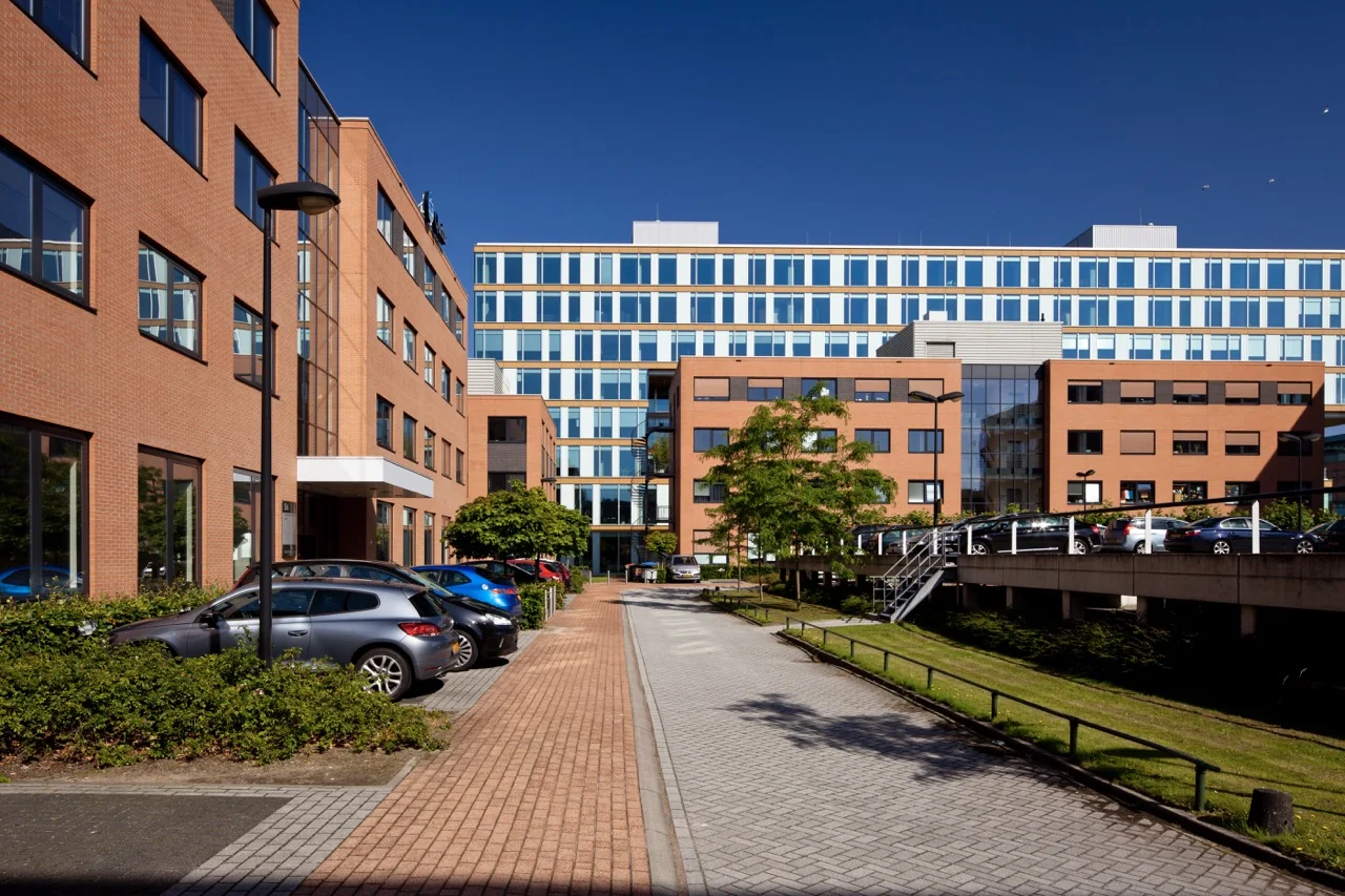 Modern kantoorgebouw aan de Lange Kleiweg 50-62 in Rijswijk met parkeerplaatsen en groenvoorziening.