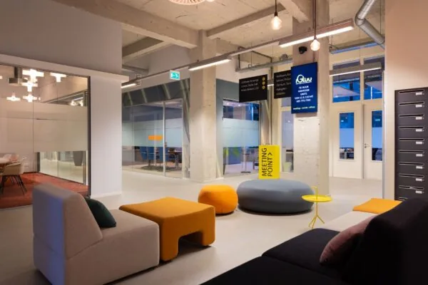 Moderne en kleurrijke ontvangstruimte in de Lichttoren 32 in Eindhoven met loungezitjes en een bord met 'Meeting Point'.