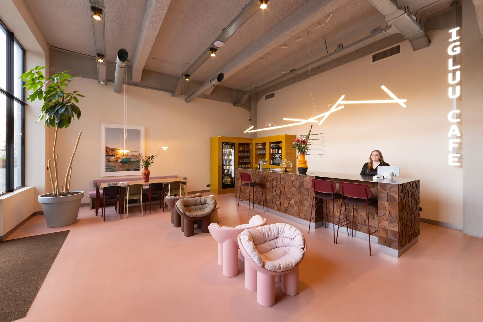 Modern ingerichte ontvangstruimte van Igluu Café in de Lichttoren 32 in Eindhoven met kleurrijke meubels en een balie met een medewerker.