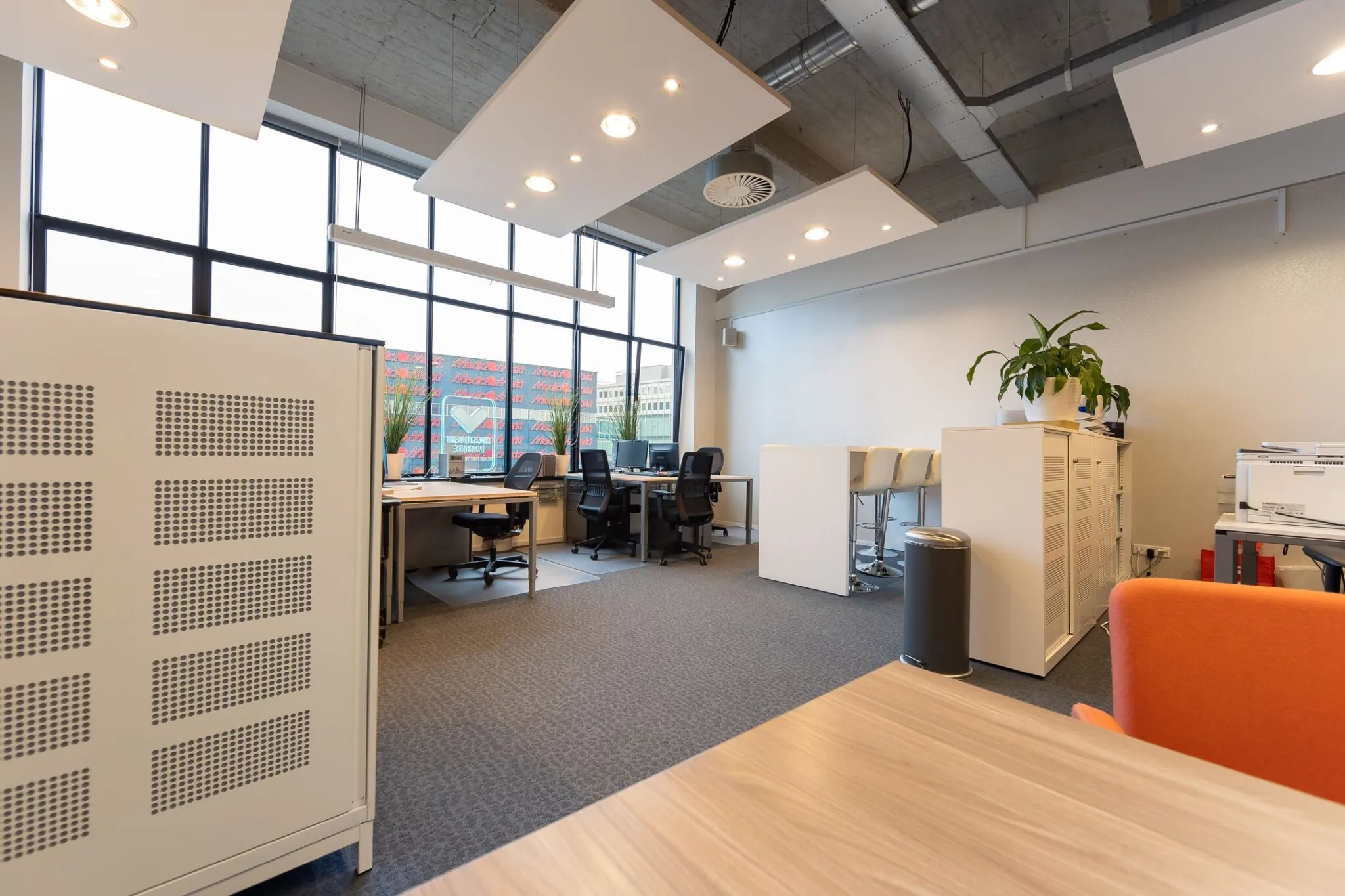 Moderne en lichte kantoorruimte in de Lichttoren 32 in Eindhoven met werkplekken, hoge stoelen en grote ramen.