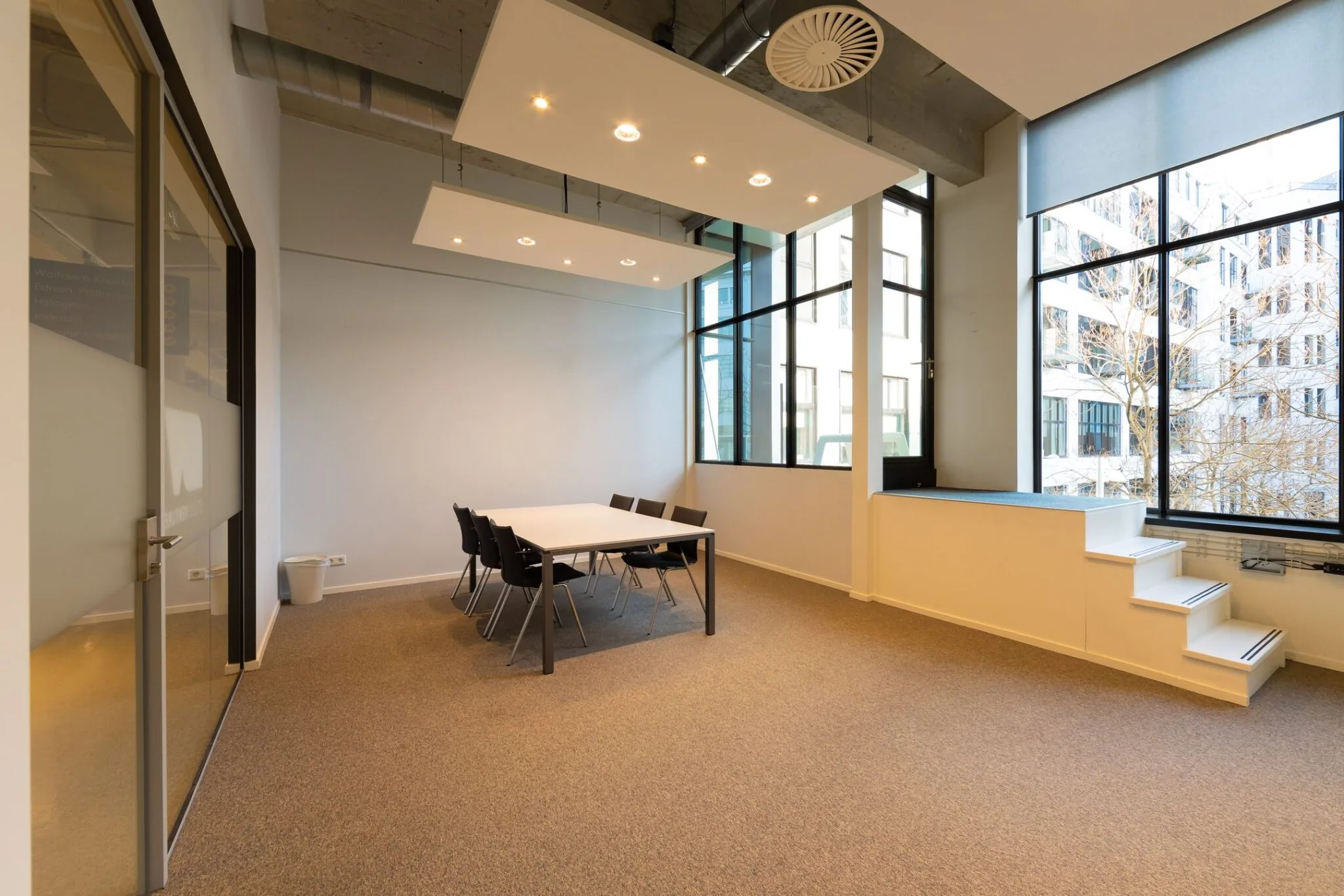 Moderne vergaderruimte in de Lichttoren 32 in Eindhoven met grote ramen, een tafel en zes stoelen.