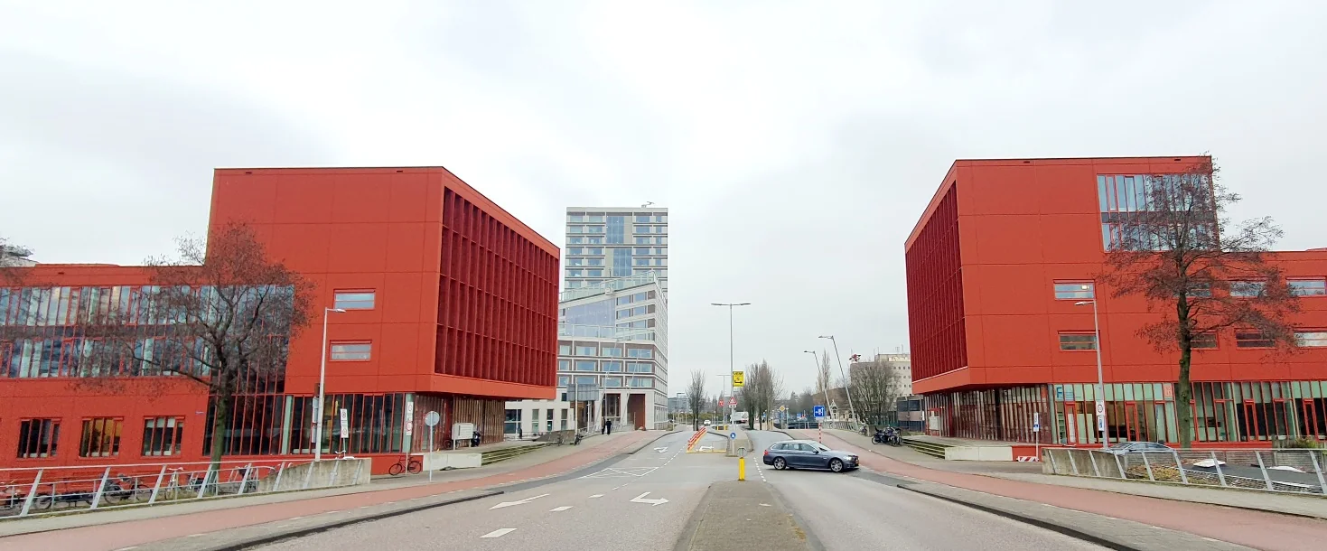 Twee felrode kantoorgebouwen aan de Panamalaan in Amsterdam met een modern hoogbouwpand op de achtergrond.