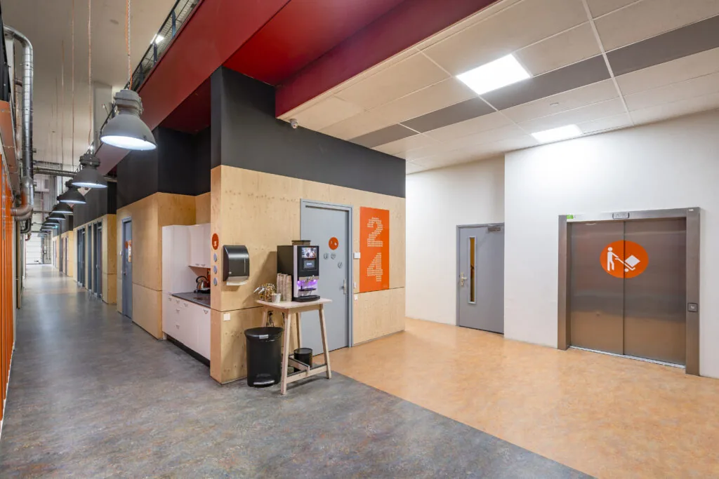 Moderne gang met koffiehoek en lift in een kantoorgebouw aan de Proostwetering 41 in Utrecht.