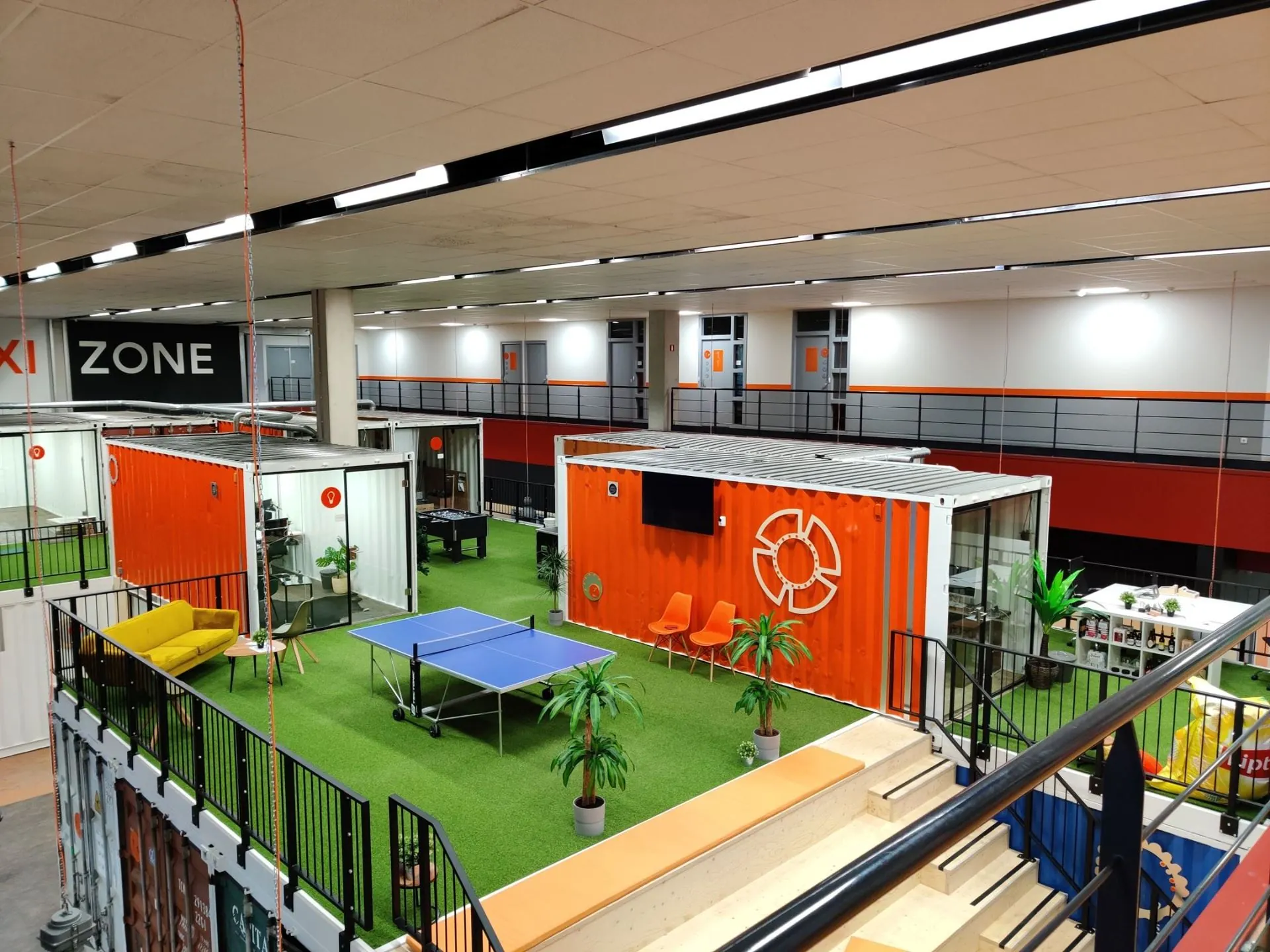 Moderne kantoorruimte aan de Proostwetering 41 in Utrecht met kleurrijke containers, kunstgras, zitplekken en een pingpongtafel.