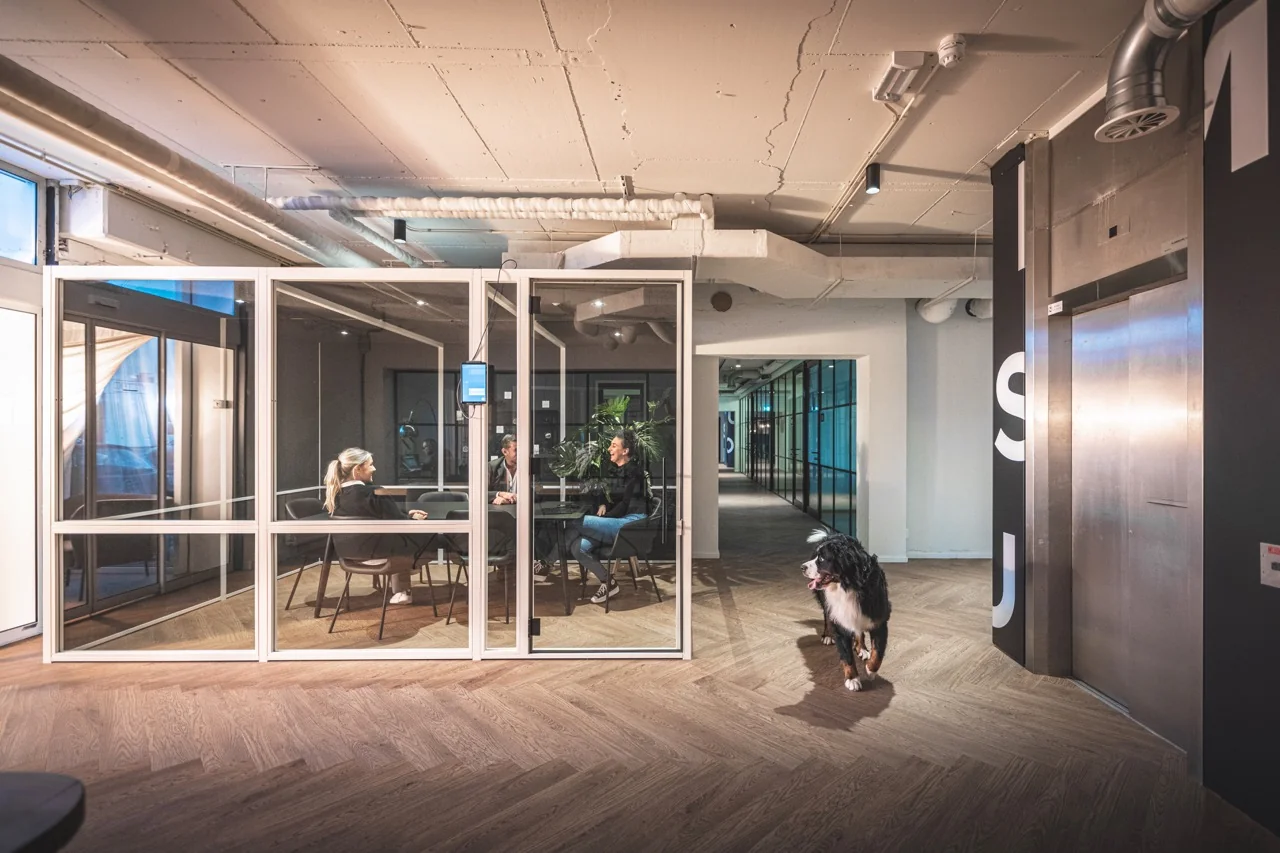 Moderne kantoorruimte aan de Rietbaan 2-12 in Capelle aan den IJssel met glazen vergaderruimte en een hond in de gang.
