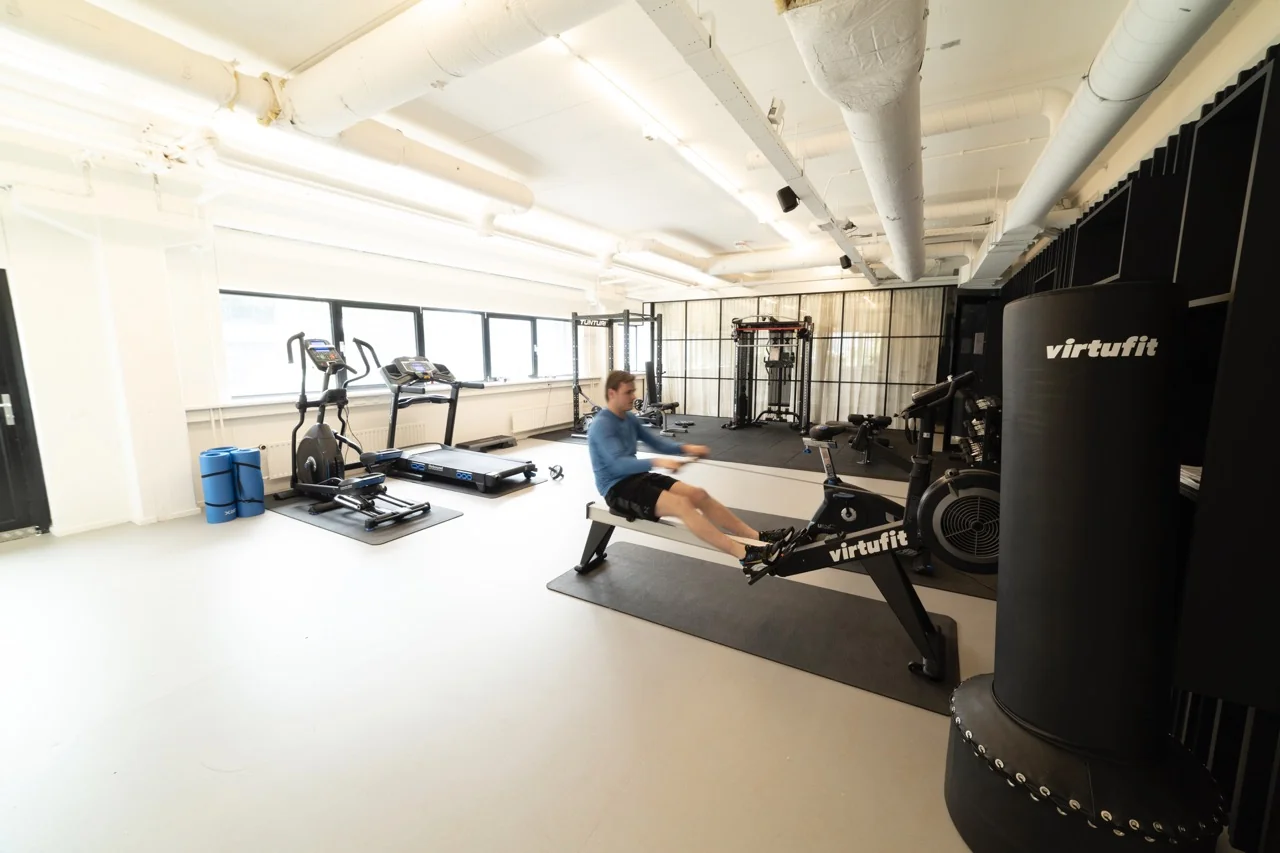 Moderne fitnessruimte in kantoorpand aan de Rietbaan 2-12 in Capelle aan den IJssel met diverse VirtuFit-apparaten en een man op een roeitrainer.