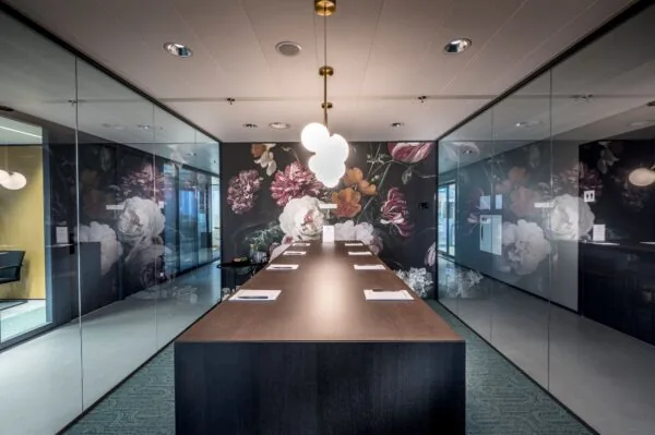 Moderne vergaderruimte in Rijnzathe 12 in De Meern met een lange tafel, glazen wanden en een opvallende bloemenmuur.