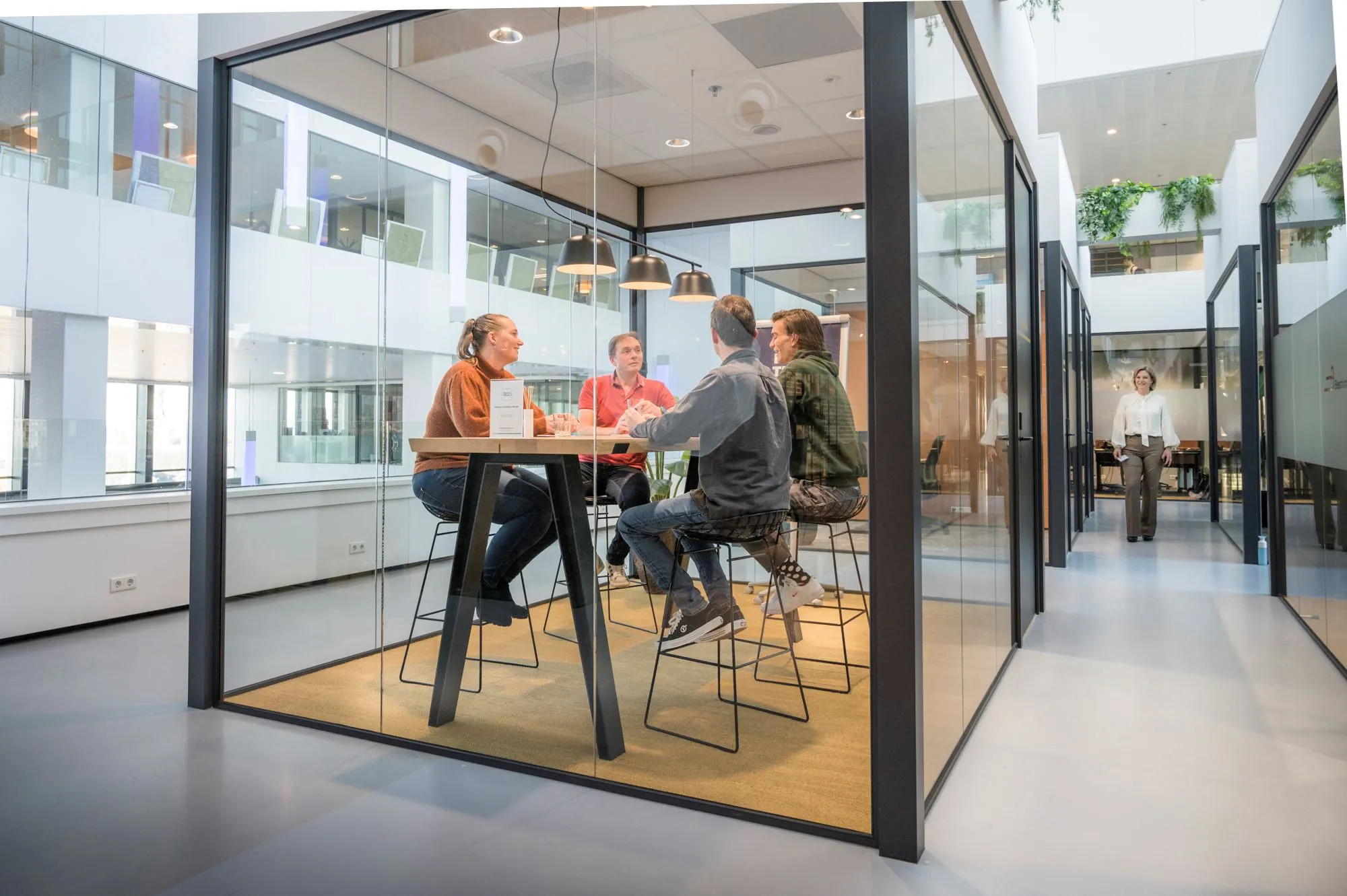 Vijf mensen in overleg in een glazen vergaderruimte in een modern kantoorpand aan Rijnzathe 12 in De Meern.