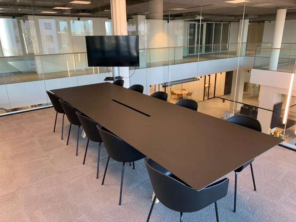 Moderne vergaderruimte met een lang zwart conferentietafel, omringd door zwarte stoelen, in een kantoorpand aan Rijnzathe 6 in De Meern.