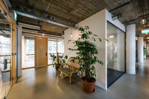 Moderne kantoorruimte aan de Singel 542 met glazen wanden, houten deuren, planten en een zithoek.