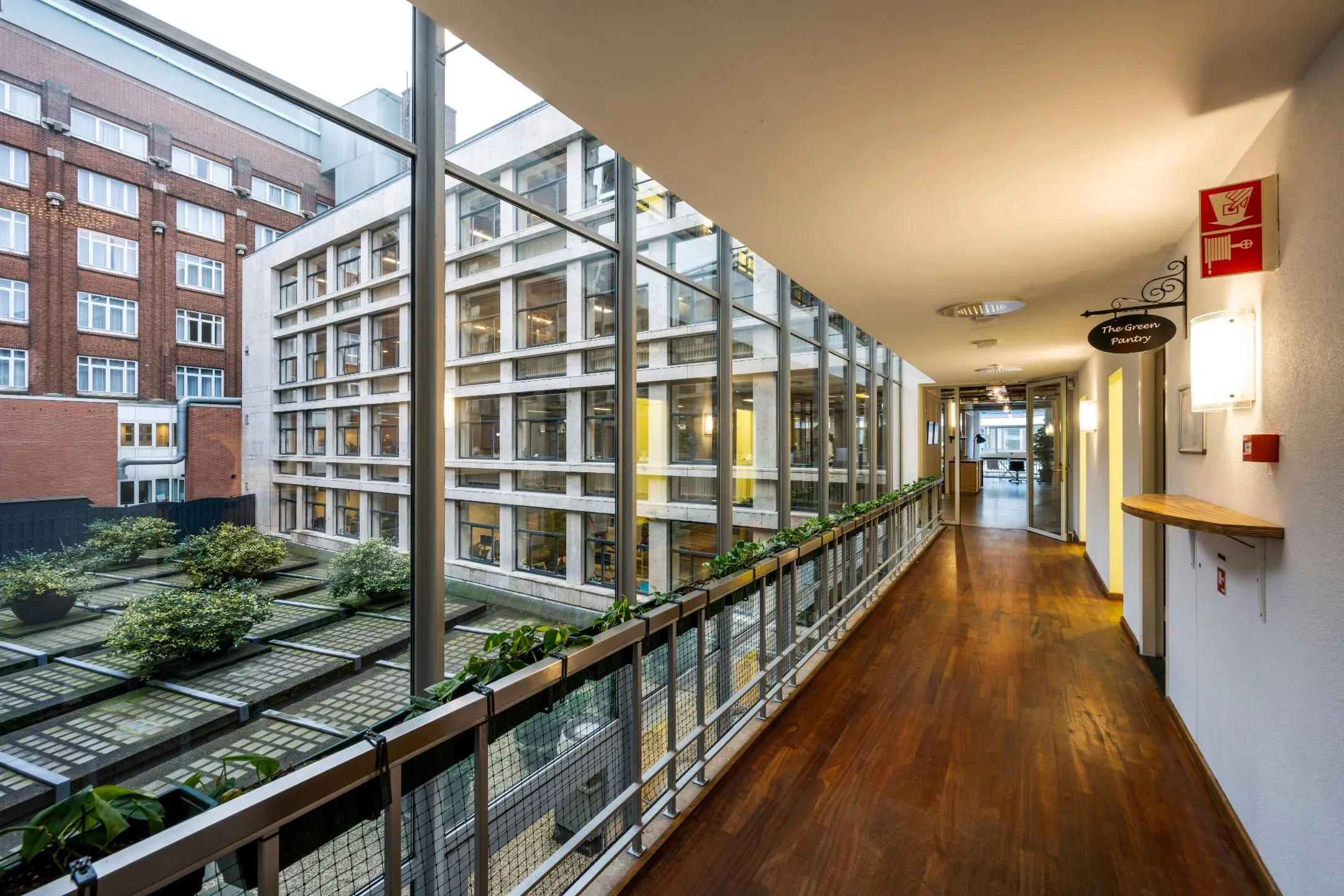 Binnenhal met houten vloer en uitzicht op moderne kantoorgebouwen aan de Singel 542 in Amsterdam.