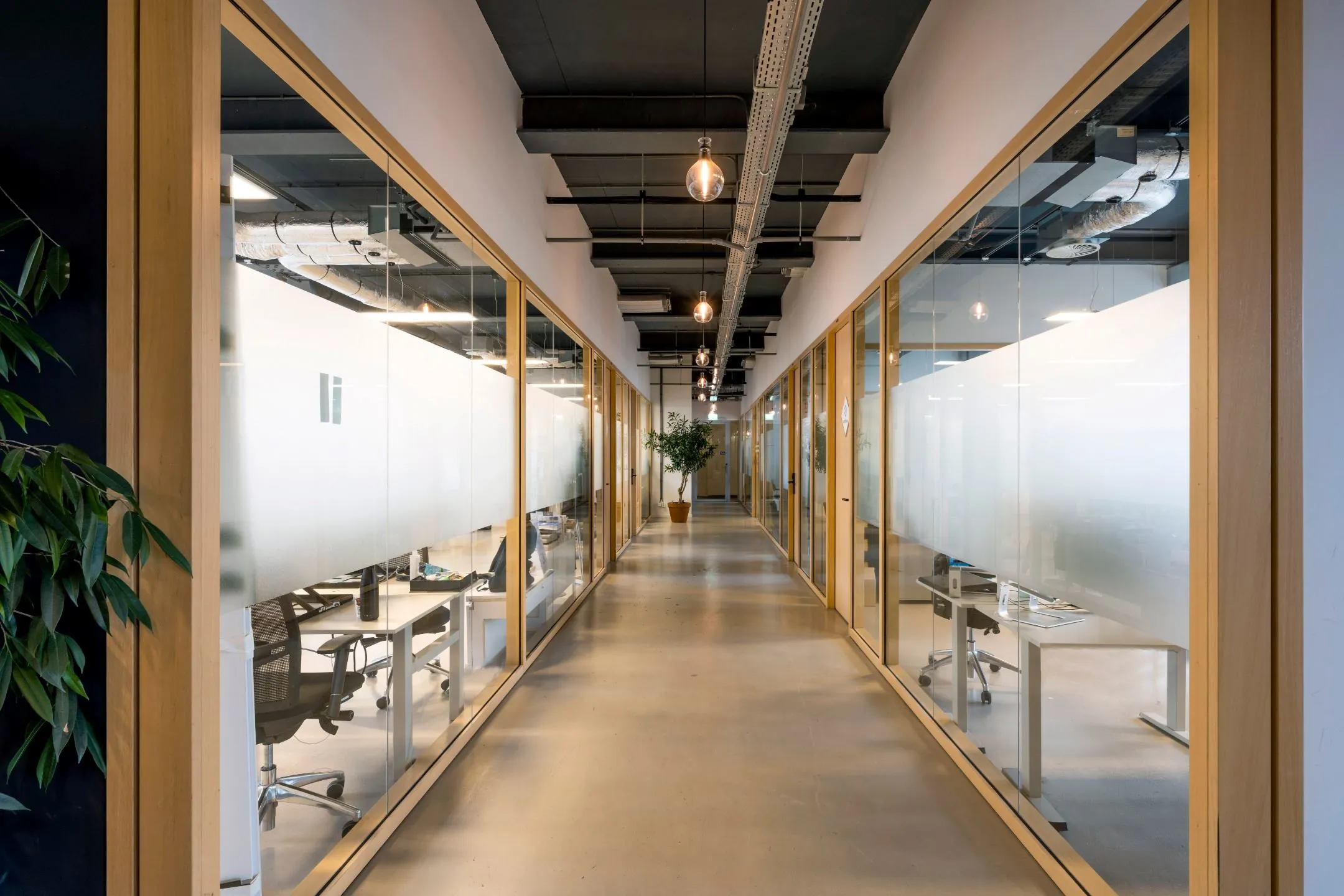 Moderne gang in kantoorruimte aan de Singel 542 met glazen kantoorwanden en industriële plafondafwerking.