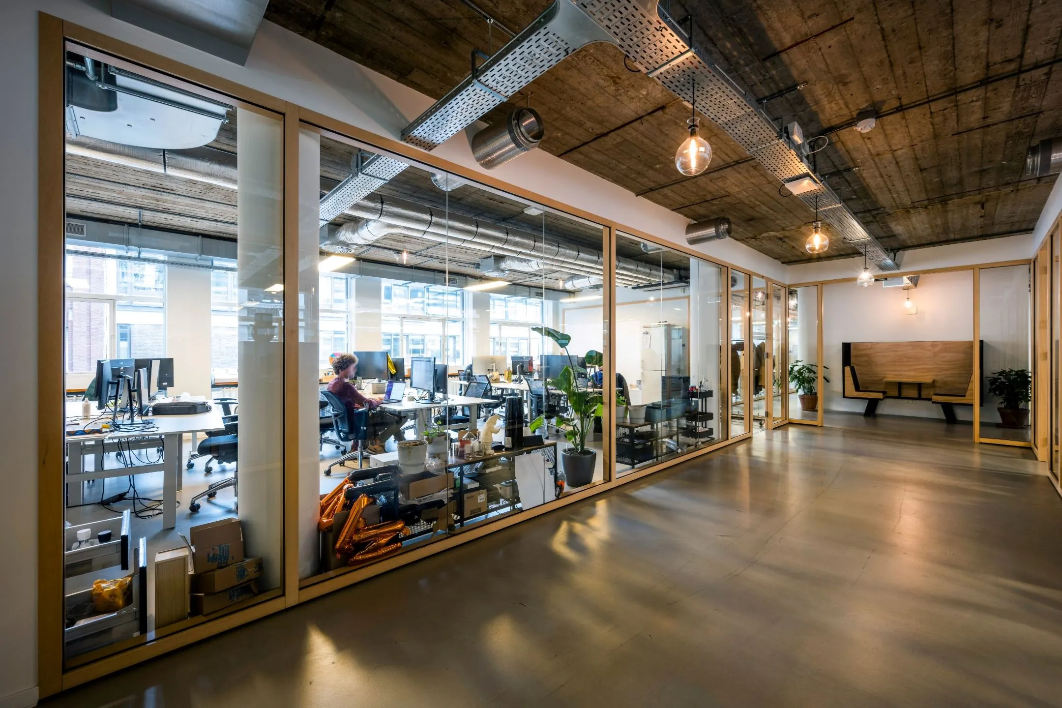 Moderne kantoorruimte aan Singel 542 met glazen wanden, werkplekken en industriële plafonddetails.