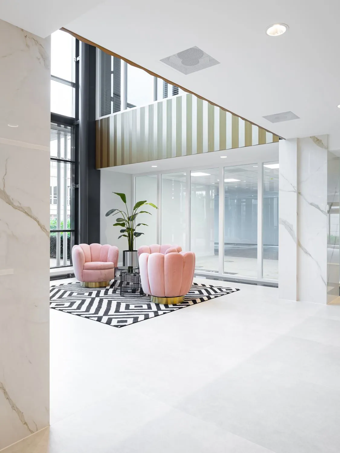 Moderne en lichte loungehoek met roze fauteuils en zwart-wit vloerkleed in de kantoorruimte aan de Siriusdreef 60 in Hoofddorp.