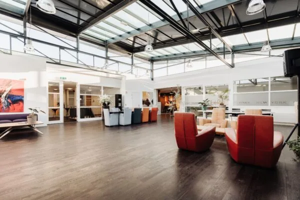 Moderne, lichte kantoorruimte aan Sloterweg 303 in Badhoevedorp met glazen dak, kleurrijke zitplekken en stijlvolle inrichting.