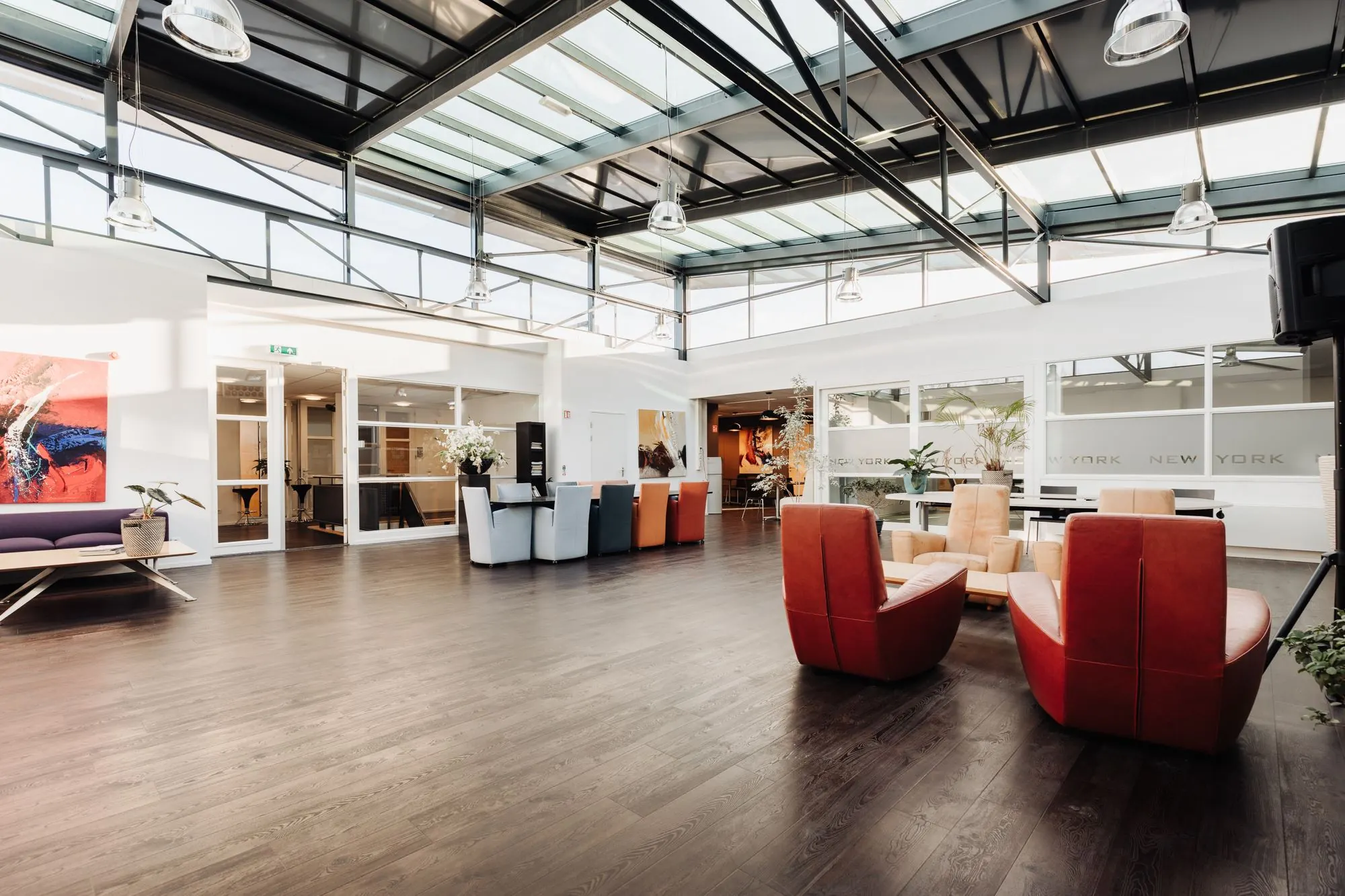 Moderne, lichte kantoorruimte aan Sloterweg 303 in Badhoevedorp met glazen dak, kleurrijke zitplekken en stijlvolle inrichting.