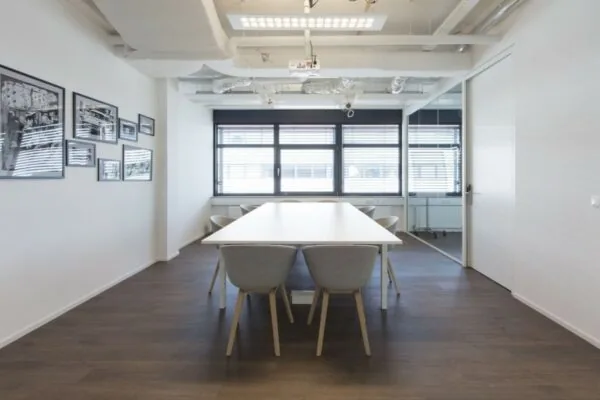 Moderne vergaderruimte met een lange witte tafel, grijze stoelen en grote ramen in een kantoor aan de St. Jacobsstraat 123-135 in Utrecht.