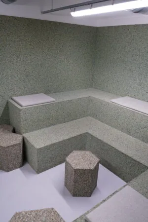 Moderne kantoorruimte in Amsterdam Weesperplein met geïntegreerde zitbanken en zeshoekige krukken van gespikkeld materiaal.