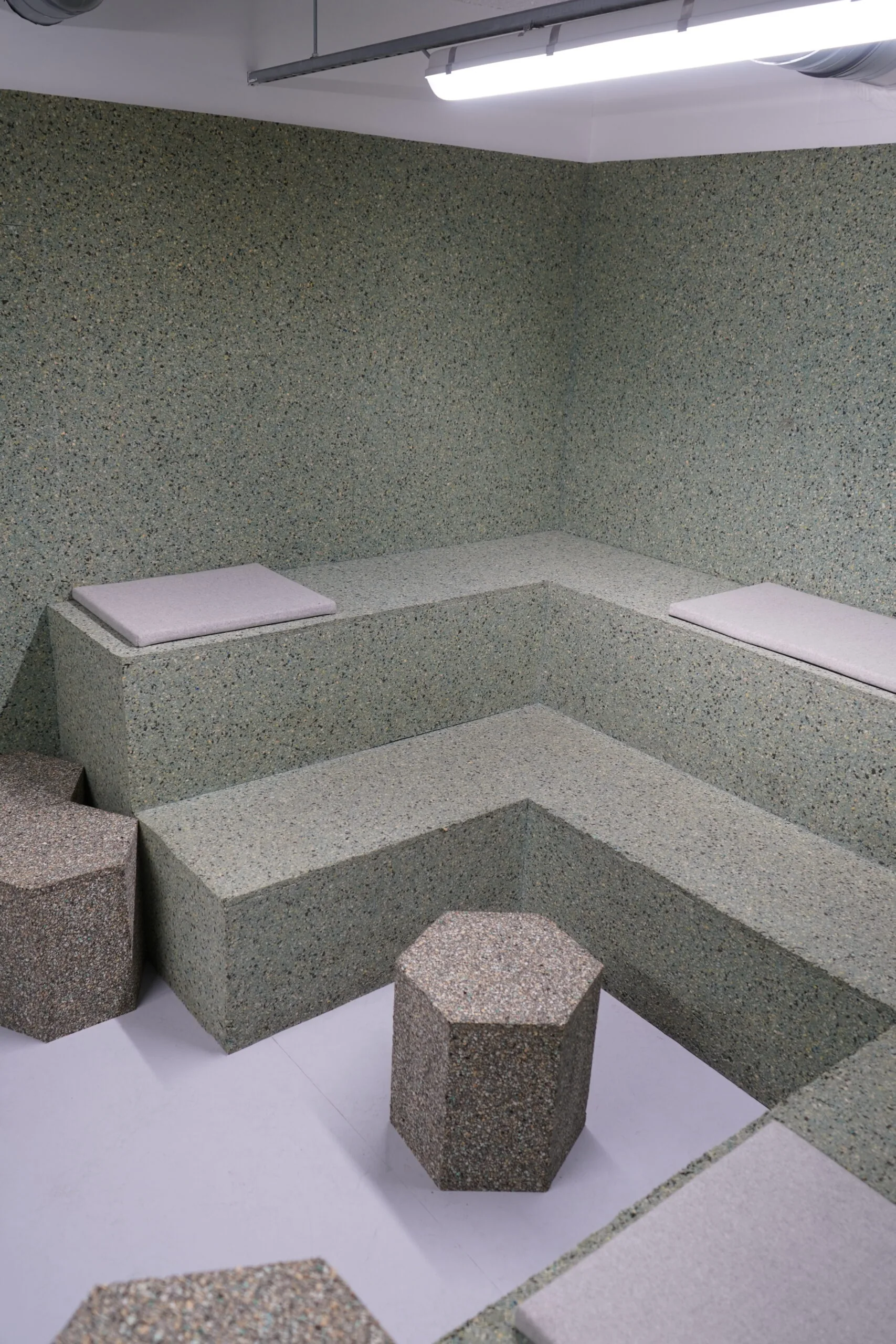 Moderne kantoorruimte in Amsterdam Weesperplein met geïntegreerde zitbanken en zeshoekige krukken van gespikkeld materiaal.