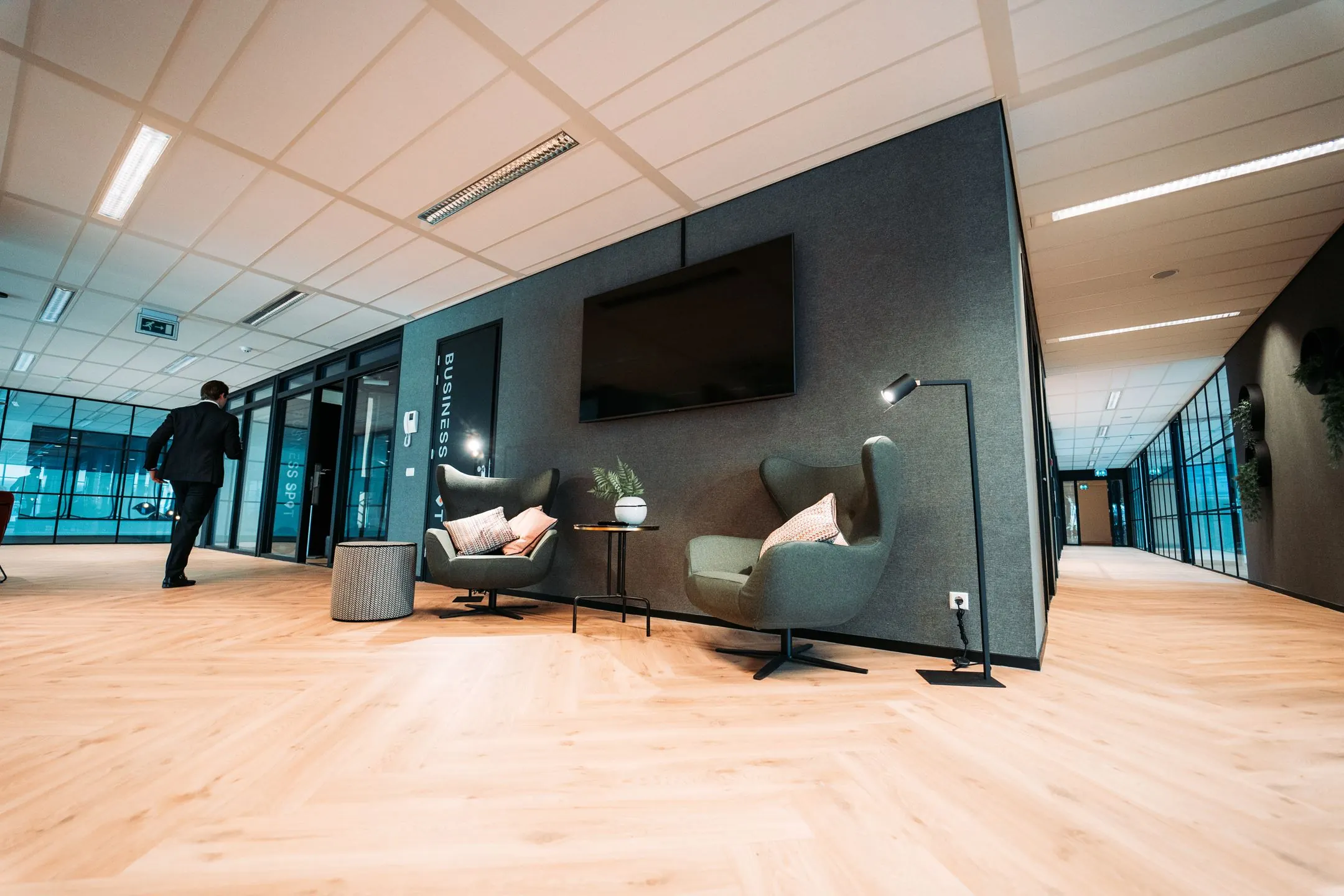 Moderne kantoorruimte aan de Lange Kleiweg 6 met loungehoek, houten vloer en glazen kantoordeuren.