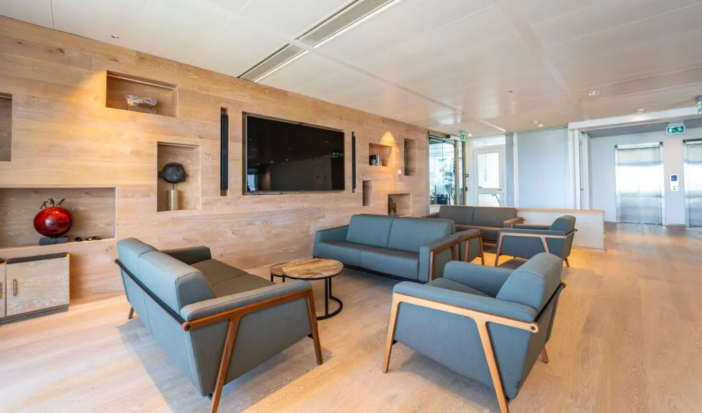Moderne wachtruimte met zithoeken en houten wand in een kantoorpand aan de Lange Kleiweg.