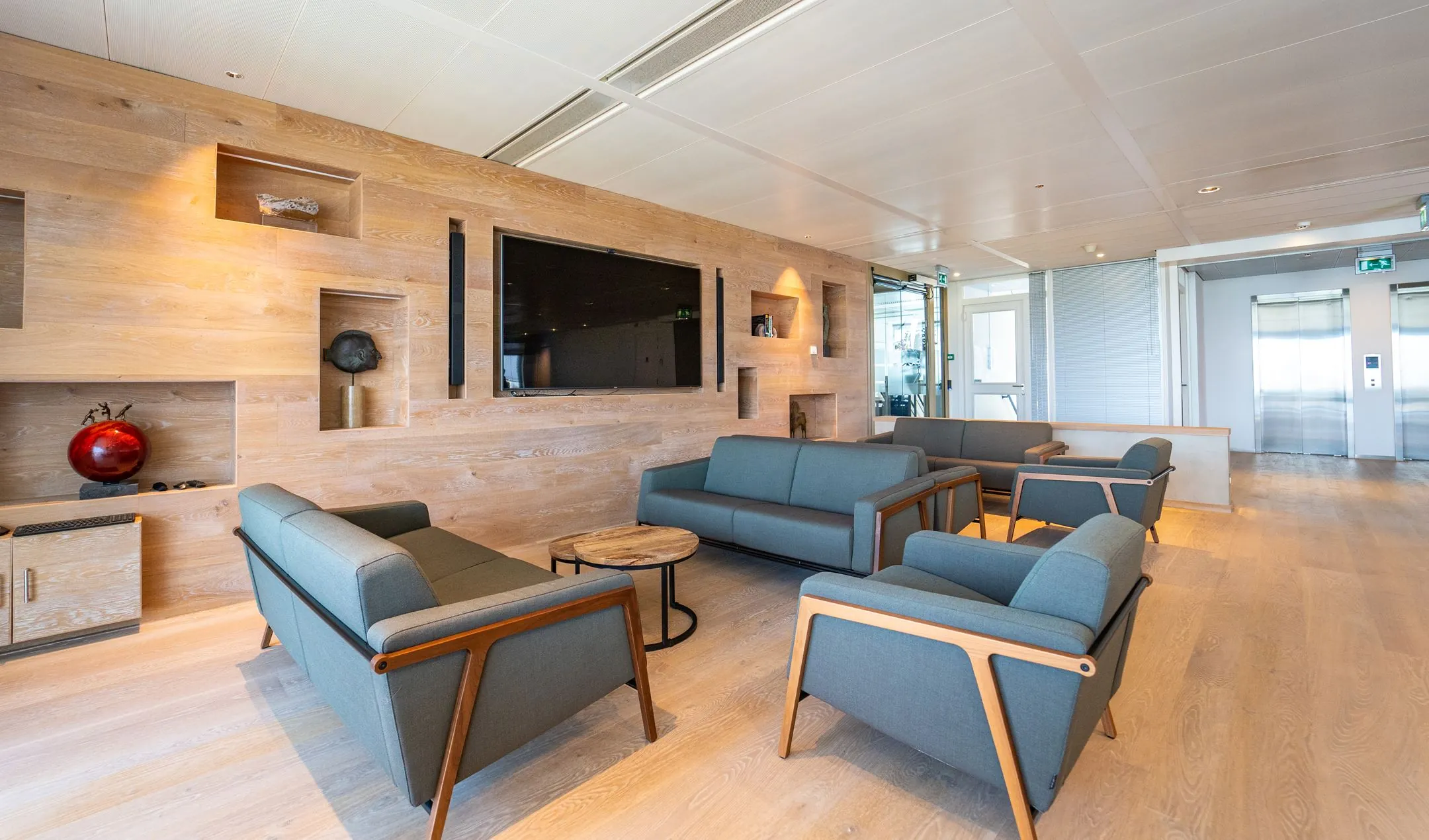 Moderne wachtruimte met zithoeken en houten wand in een kantoorpand aan de Lange Kleiweg.