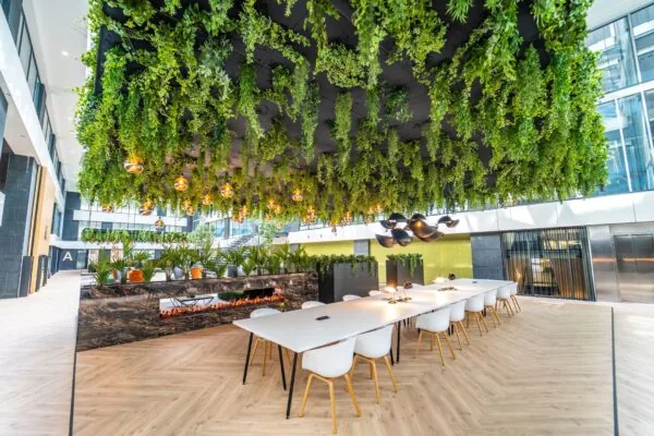 Moderne kantoorruimte aan de Lange Kleiweg met groene plafonddecoratie, lange werktafels en een stijlvolle open haard.