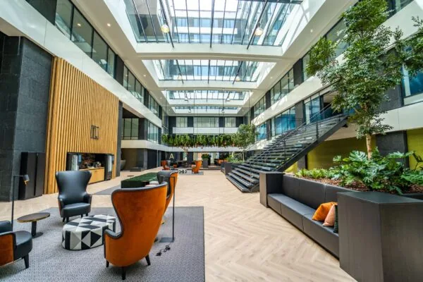 Moderne en lichte kantoorruimte aan de Lange Kleiweg met grote glazen overkapping, zitgedeeltes en veel groenvoorziening.