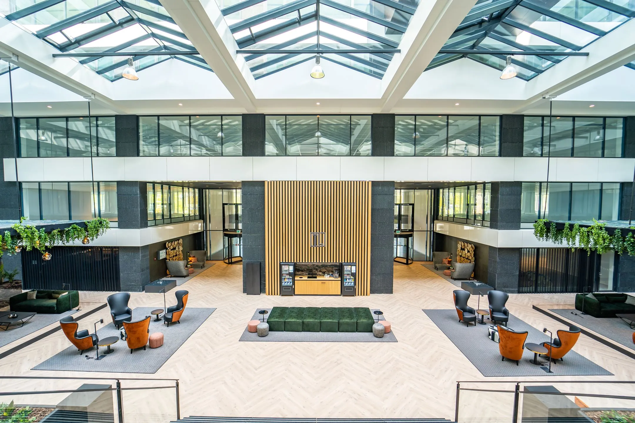 Moderne en lichte kantoorlobby aan de Lange Kleiweg 6-28 met zitgedeeltes, planten en glazen dakconstructie.