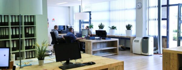 Moderne kantoorruimte aan de Kanaaldijk-Zuid 19 met houten bureaus, werkende medewerkers en veel daglicht.