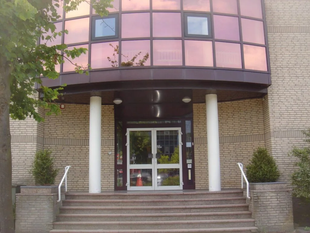 Hoofdingang van het kantoorgebouw aan Kanaalpark 157 met trap, glazen deuren en rozegetinte ramen.