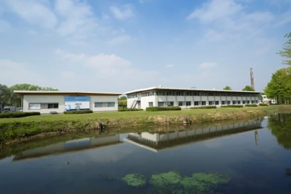 Bedrijfsverzamelgebouw aan de Steenovenweg 5 met weerspiegeling in een vijver op een zonnige dag.