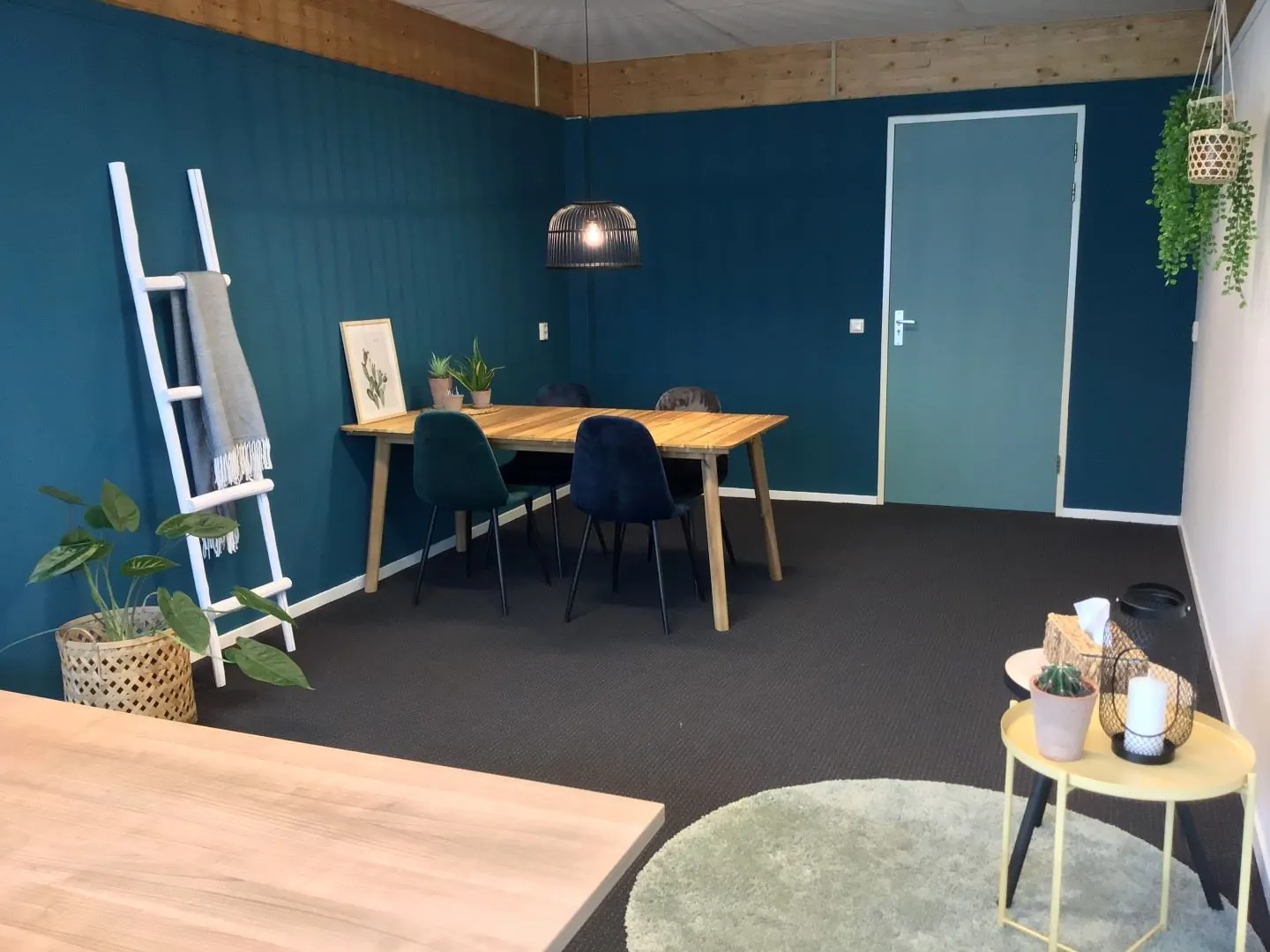 Moderne kantoorruimte aan de Steenovenweg 5 met houten vergadertafel, donkergroene muur en sfeervolle planteninrichting.