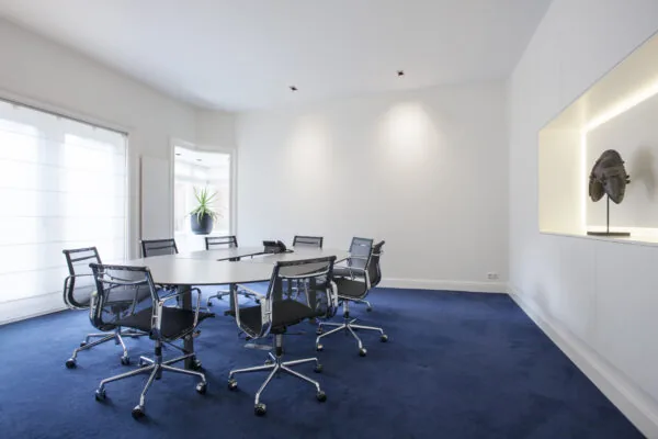 Moderne vergaderruimte met blauwe vloerbedekking en zes stoelen in kantoorruimte Sweelinckplein 1.