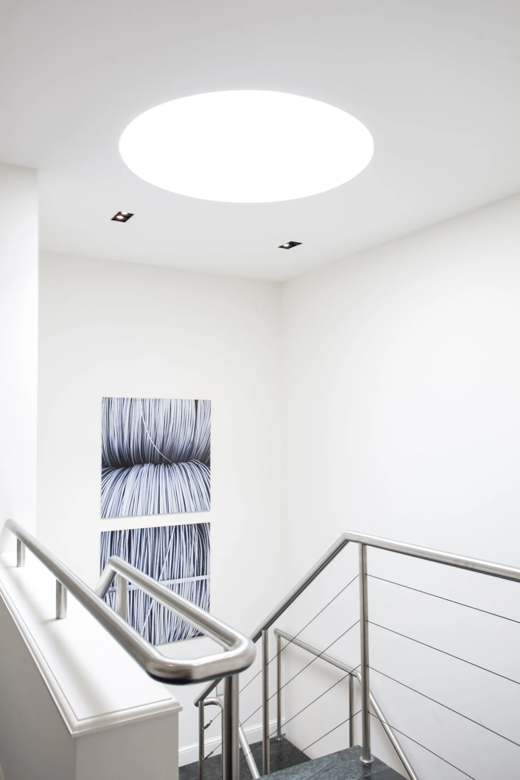 Moderne en lichte trapopgang met roestvrijstalen leuning en abstracte kunst in kantoorruimte aan Sweelinckplein 1.